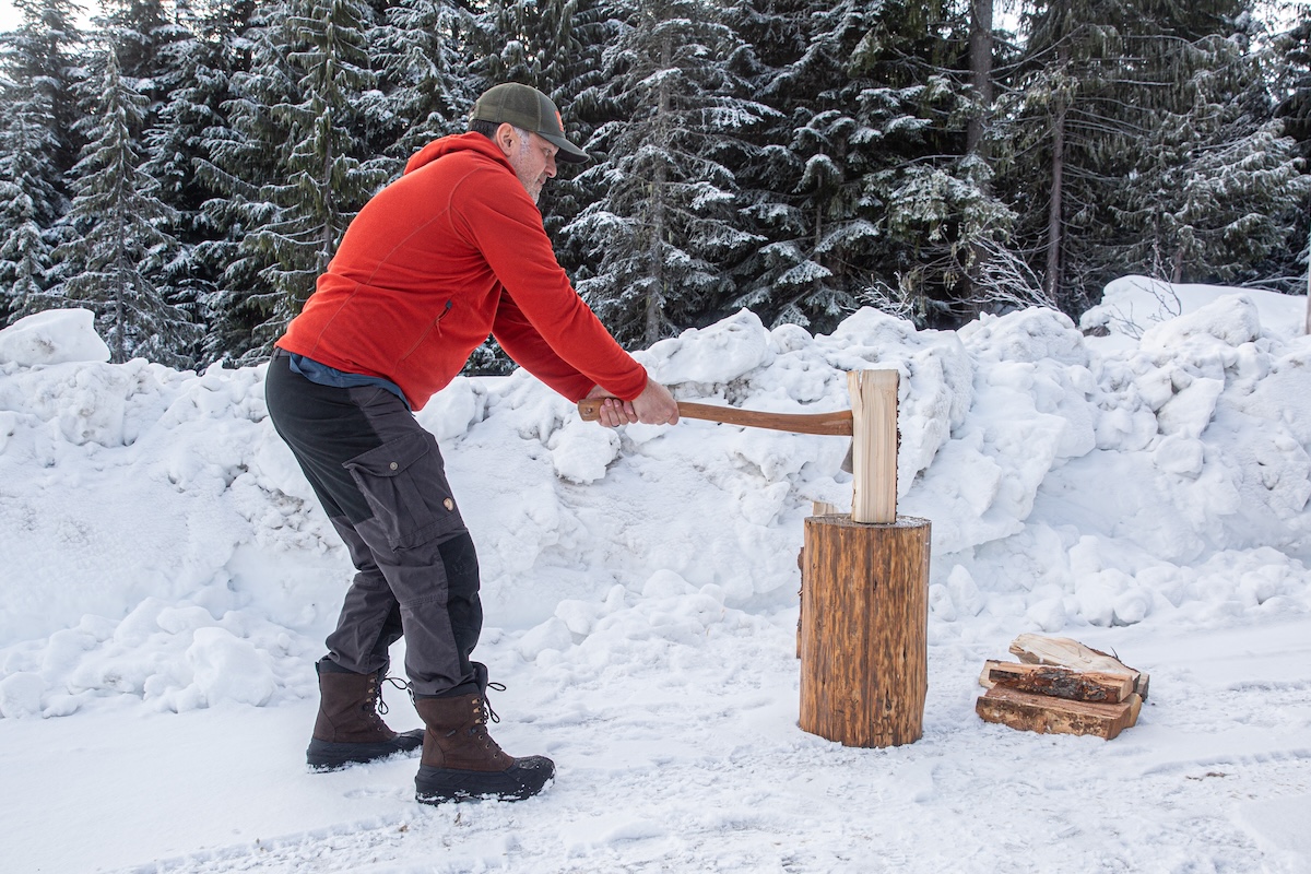 A man out in the snow chopping wood