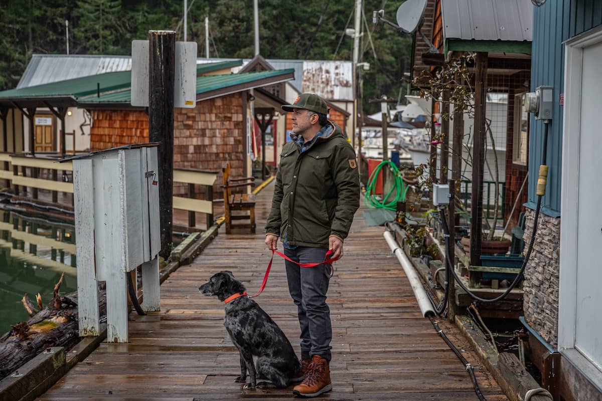 A man pauses on a dock while out walking his dog