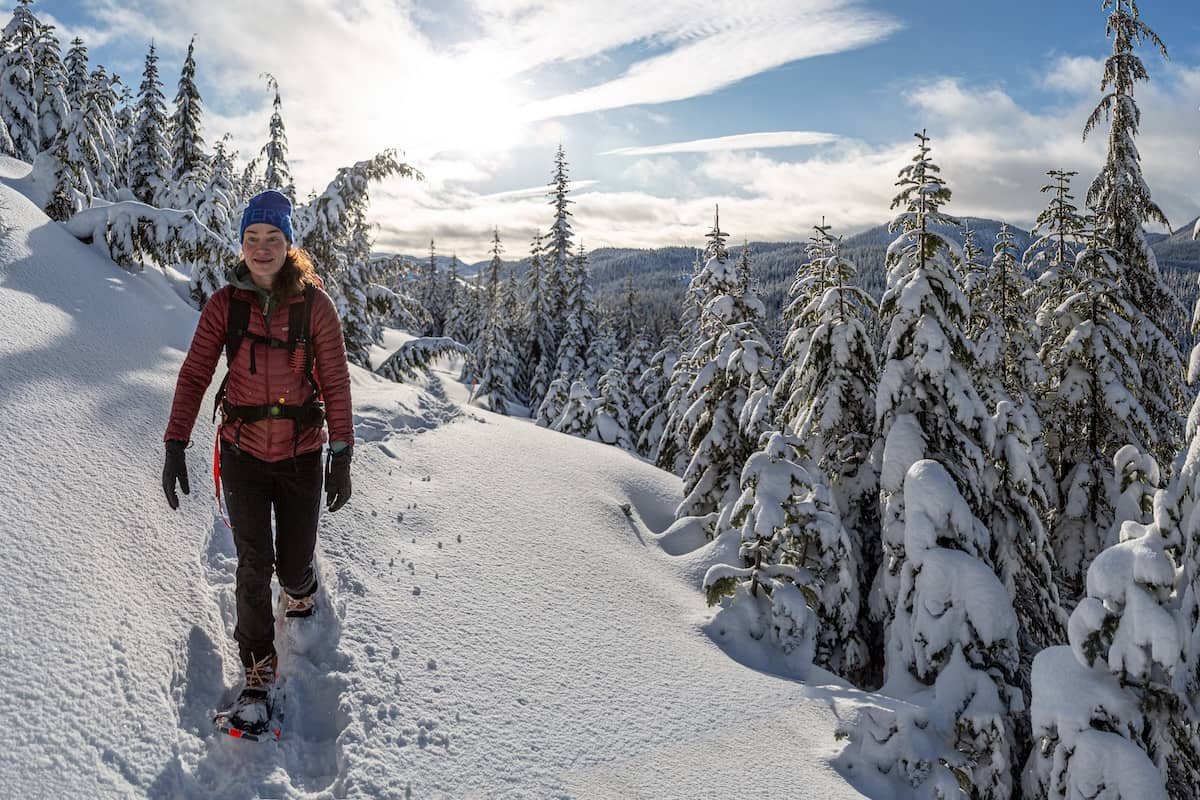 A woman snowshoeing in the mountains on a sunny and snowy day