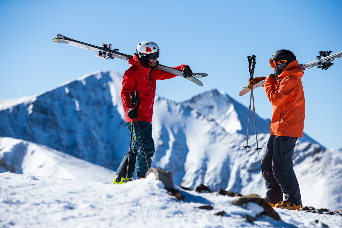 How to choose a ski jacket (two skiers with skis on shoulders)