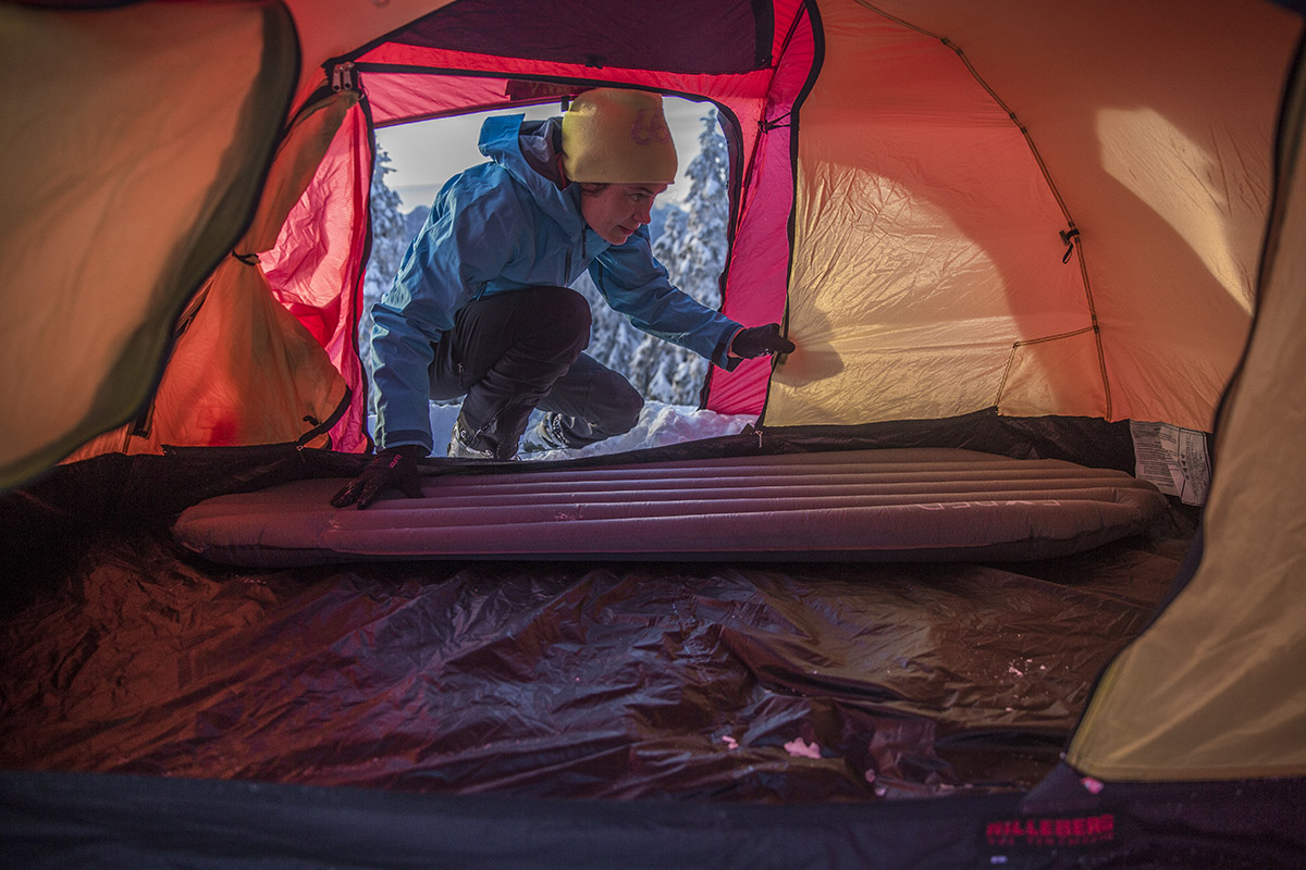 A camper inflates their mattress pad inside a tent on a cold day.