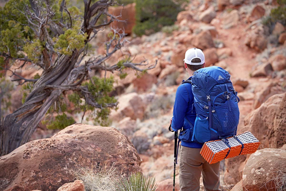 A backpacker carries an egg crate style foam pad on their pack.