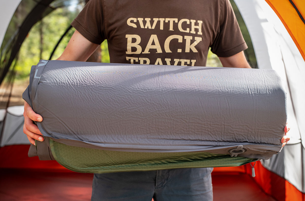 A tester holds a deflated and rolled sleeping pad.
