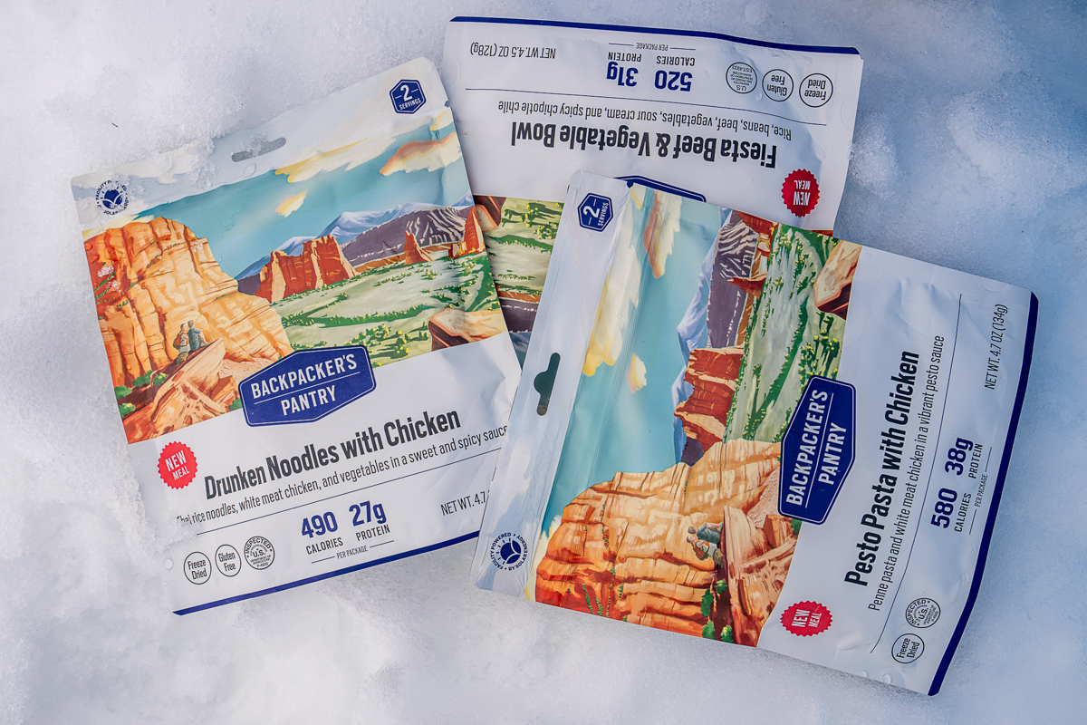 Three backpacking meal packages on snow