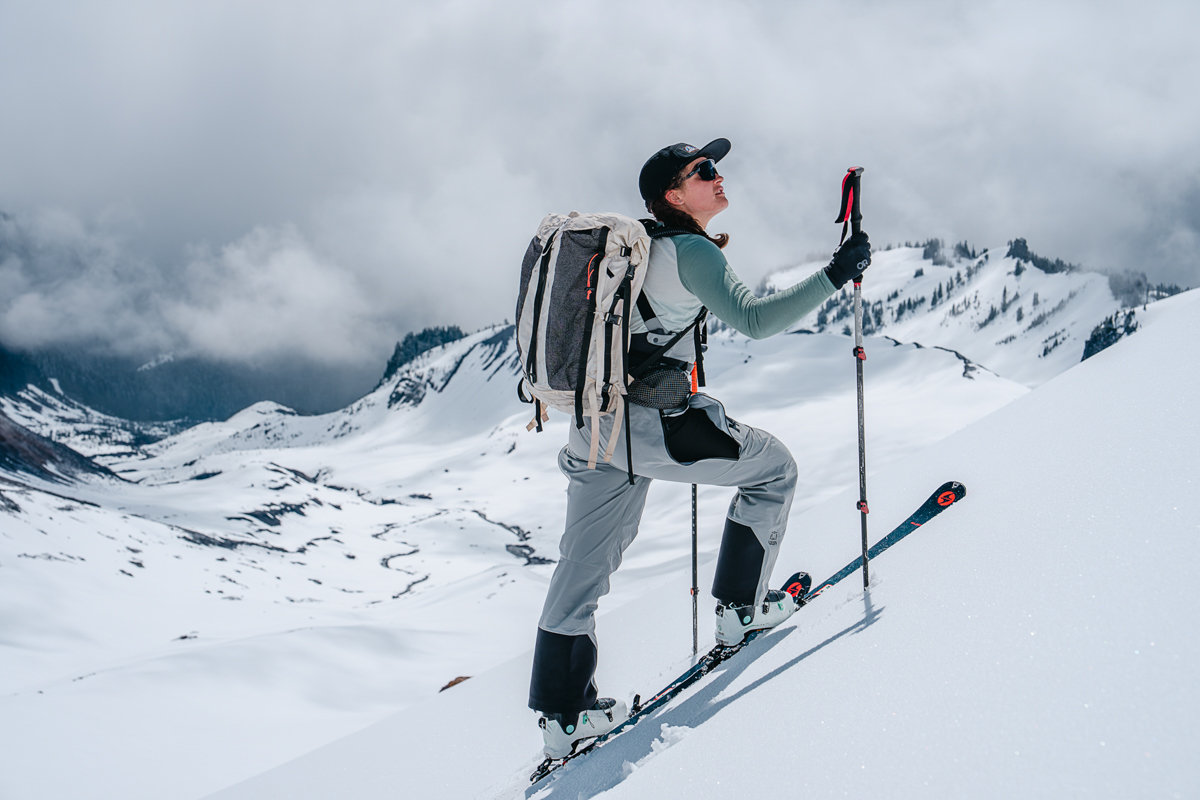A woman skinning up a steep snowy slope