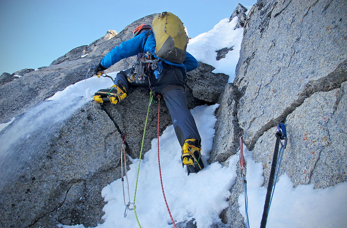 A climber uses crampons to stick into vertical snow.