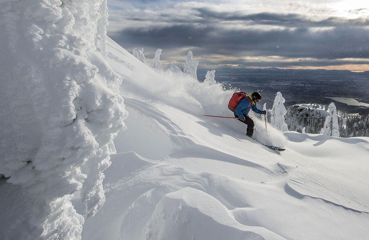 A man skis quickly downhill through deep snow