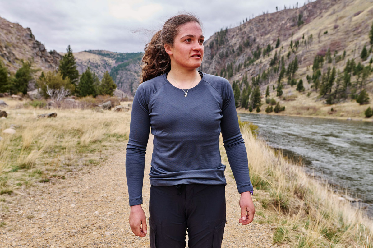 A woman wearing a blue baselayer walks next to a river