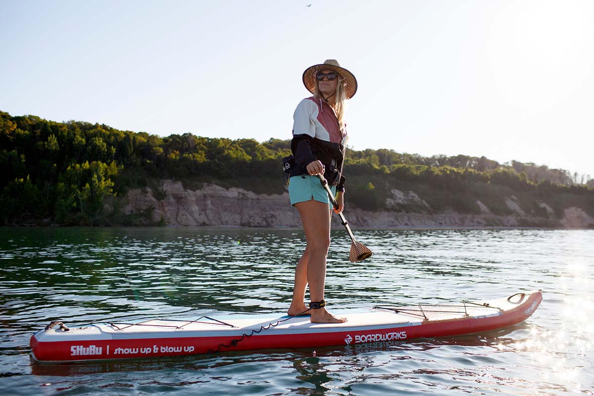 A woman paddling a stand-up paddleboard on a beautiful mountain lake. 