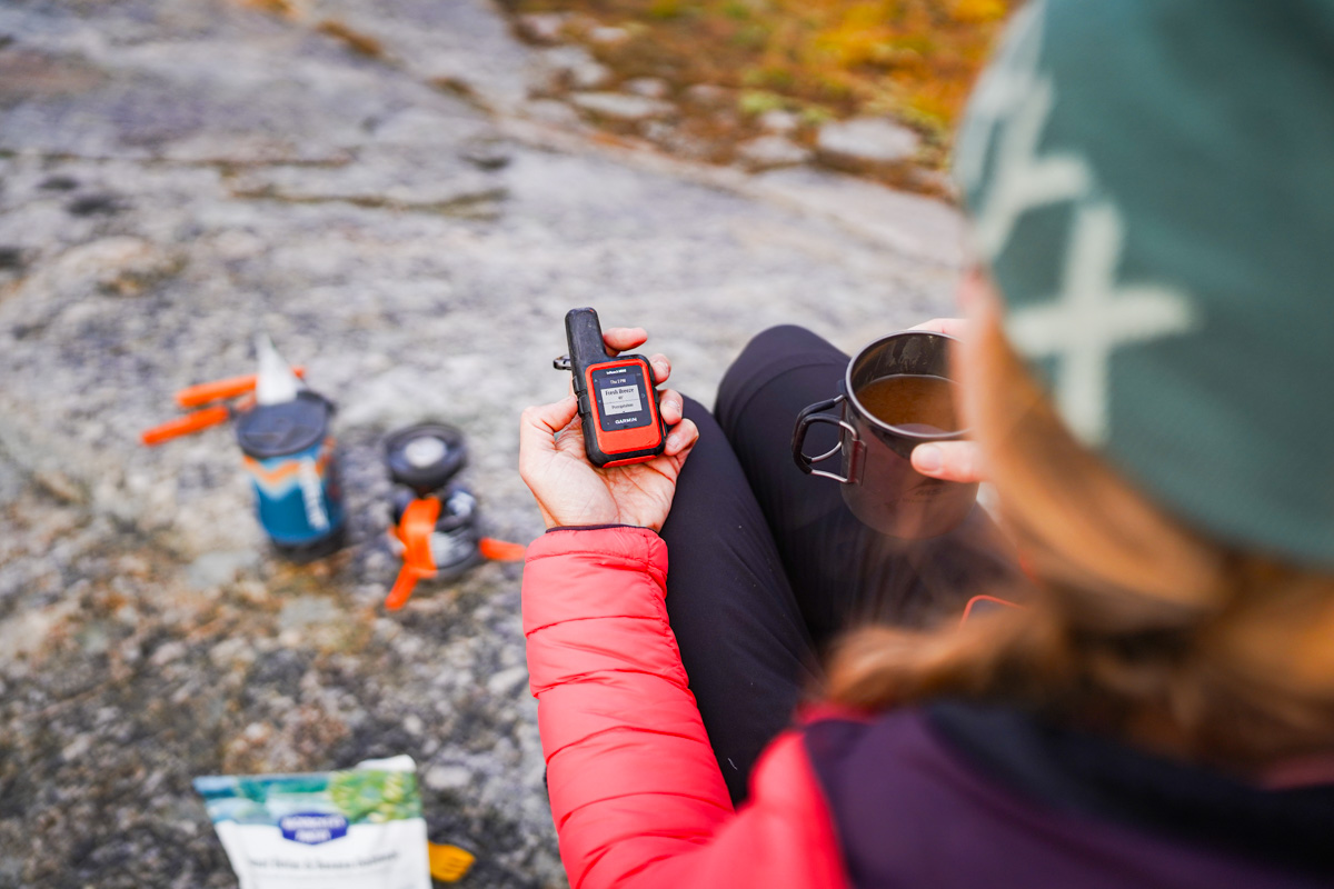 A closeup of the Garmin inReach Mini2 in someone's lap while on a backpacking trip