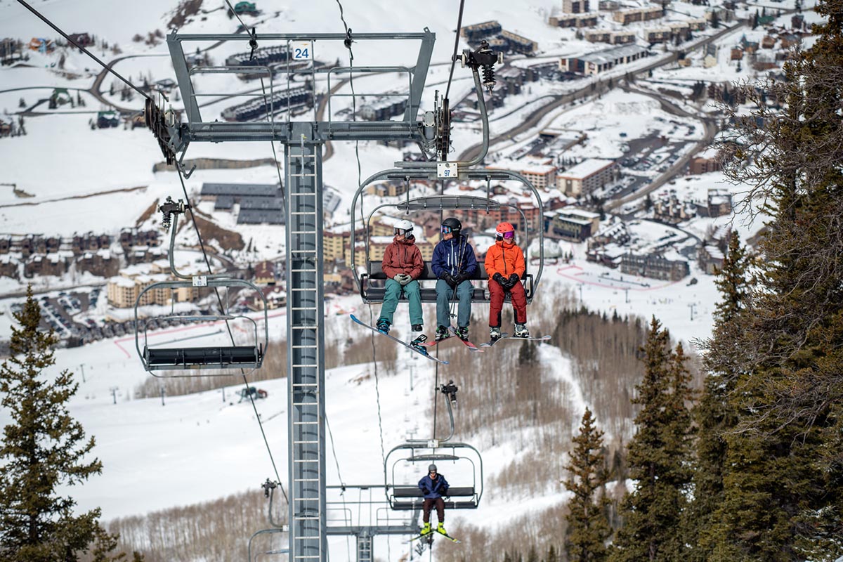 A group of skiers ride up the ski lift. 