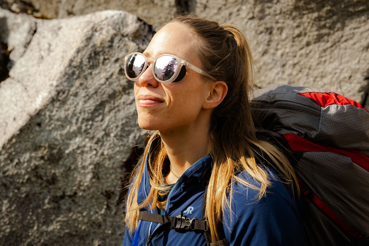 A woman hiking in the mountains wears sport sunglasses.