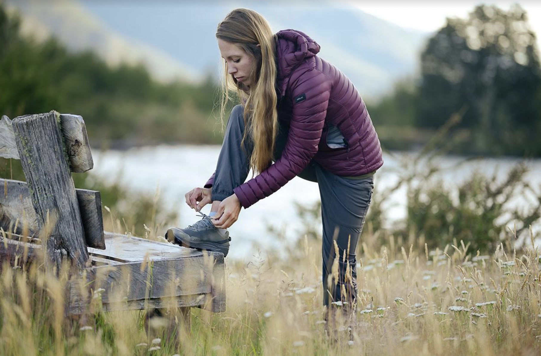 A woman is tying her hiking shoes on a bench