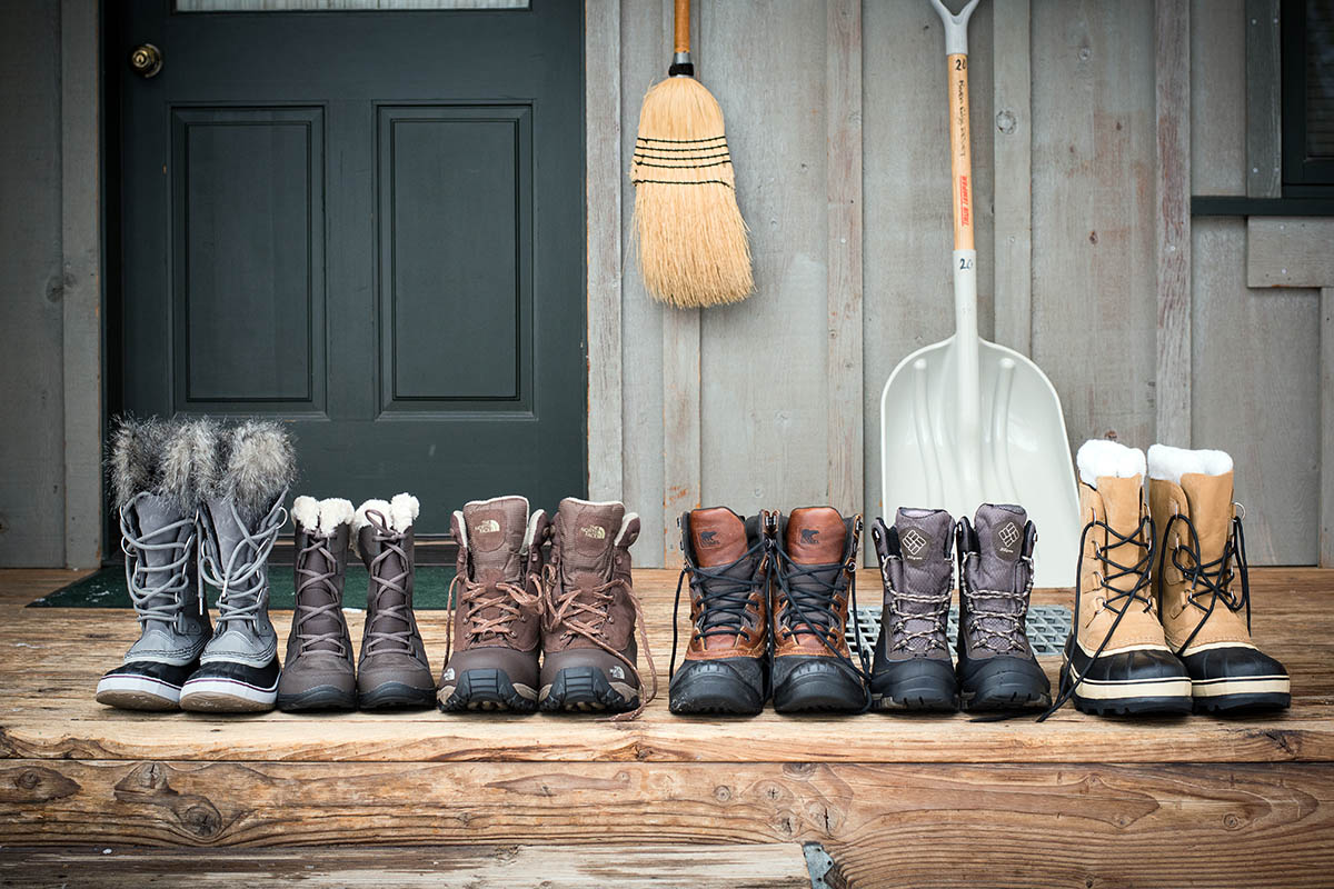 A lineup of six different kinds of winter boots set out on a porch