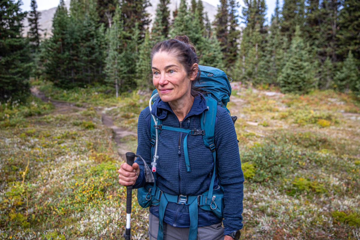 A woman backpacking in a blue fleece midlayer
