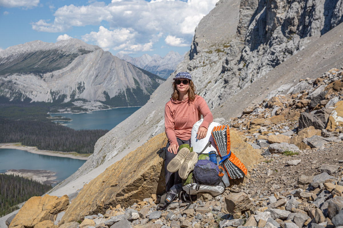 A woman leaning on her backpack on a rocky trail.