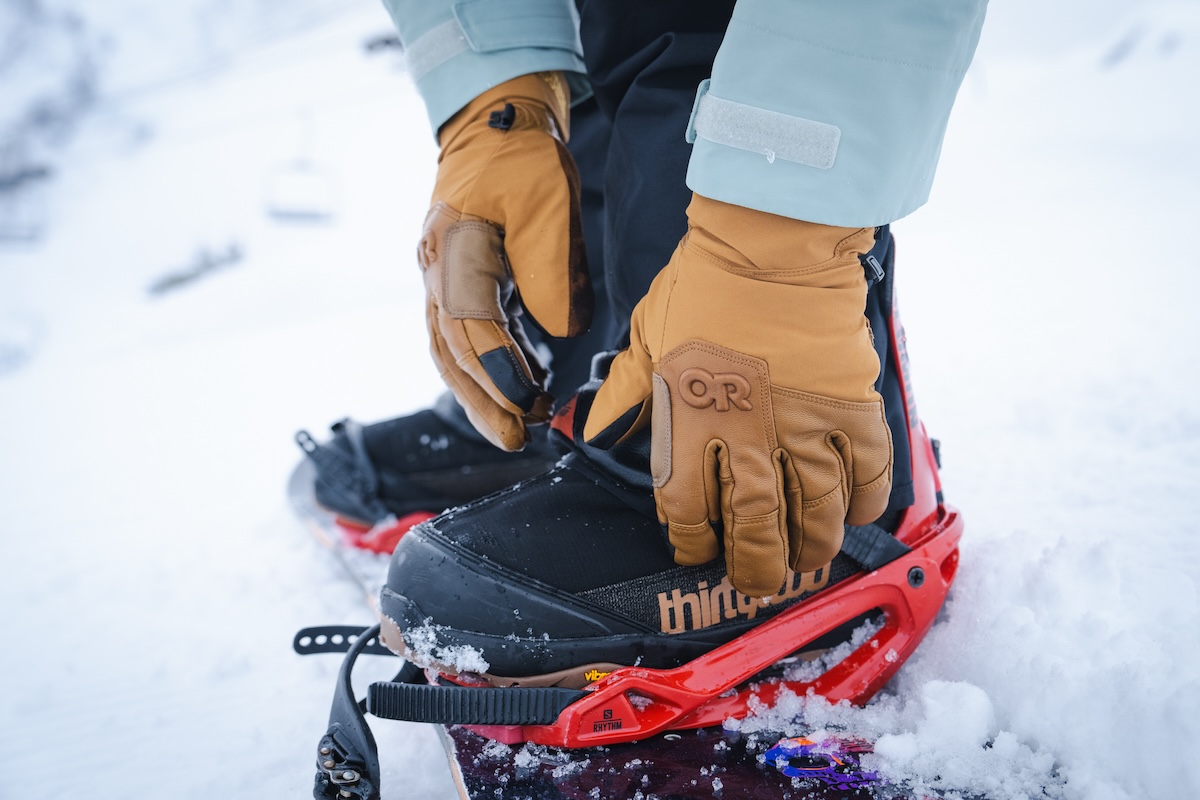 Close up photo of a person strapping into a snowboard binding