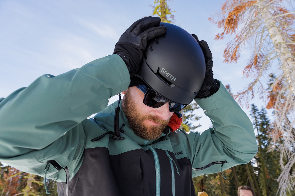 A snowboarder puts on his helmet and gets ready to ride. 