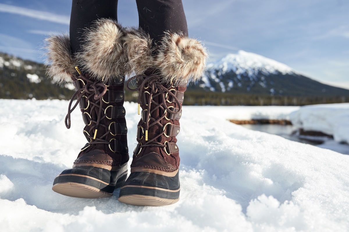 An up close shot of the Sorel Joan of Arctic with a lake and snow in the background.