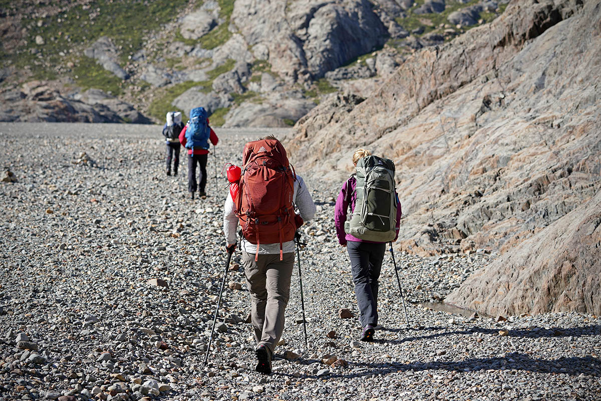 A group of hikers all wearing large backpacks walk away from the camera 