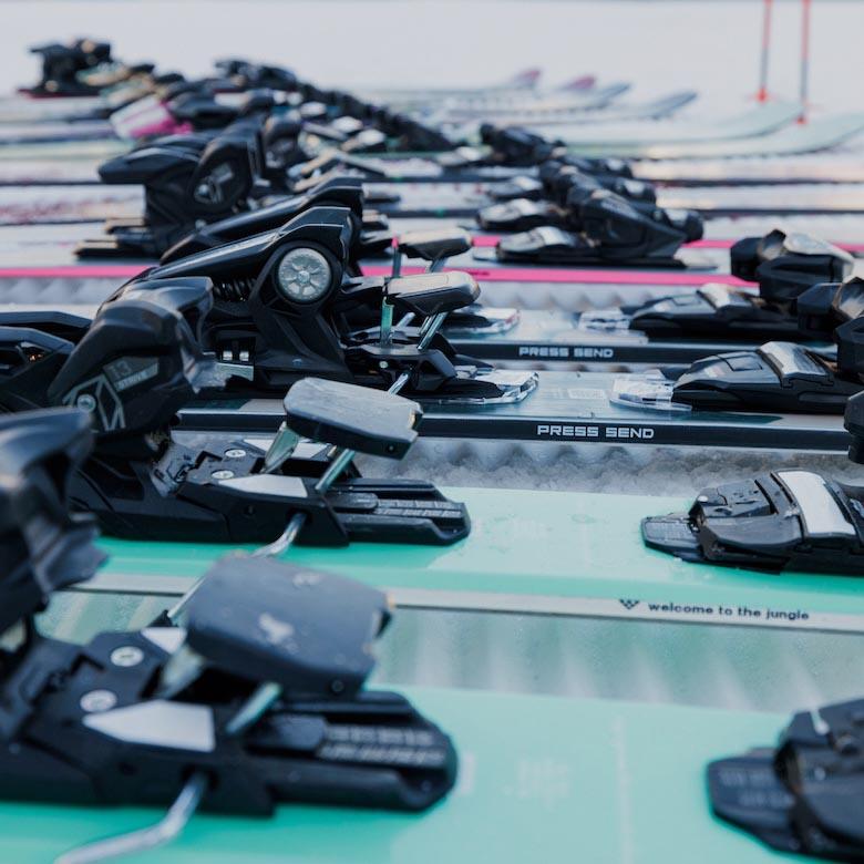 A close up of many ski bindings lined up on the snow