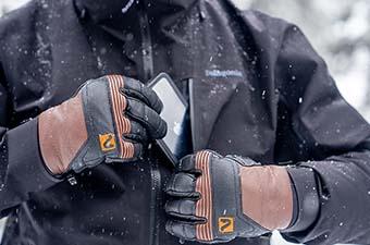 A skier puts their phone in the chest pocket of their jacket during storm